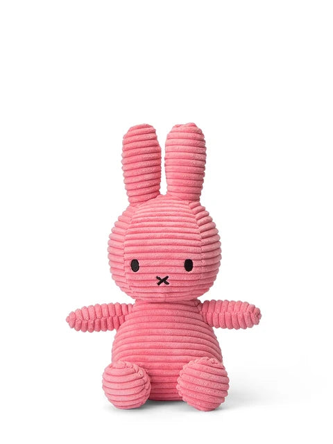 A pink, corduroy stuffed bunny toy is sitting upright on a white background.