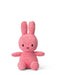 A pink, corduroy stuffed bunny toy is sitting upright on a white background.