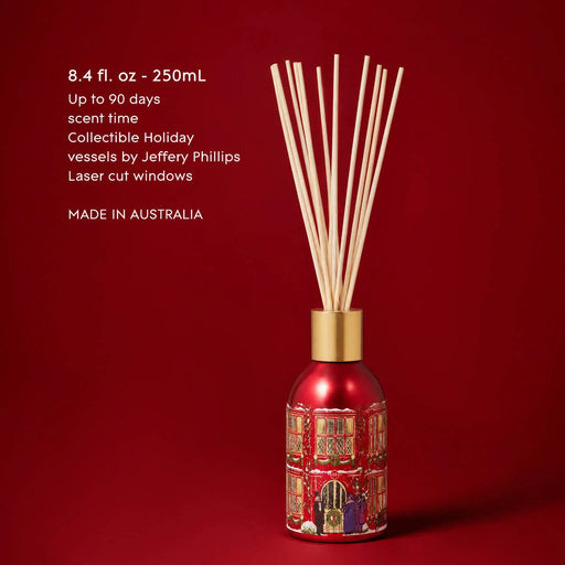 A red diffuser with a gold-colored base, filled with white sticks, against a red background.