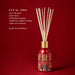 A red diffuser with a gold-colored base, filled with white sticks, against a red background.