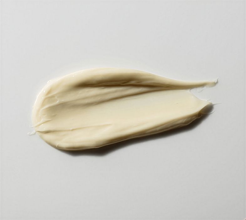 A small amount of cream is spread across a white surface.