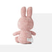 A pink stuffed bunny toy is sitting on a white surface.