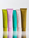five tubes of body lotion arranged in a row, each with a different color.