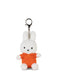 A small white stuffed bunny wearing an orange shirt and sitting on a white surface.