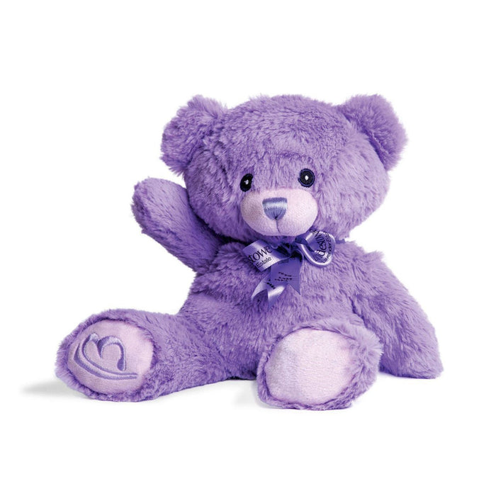 A purple teddy bear with a bow around its neck is sitting on a white background.