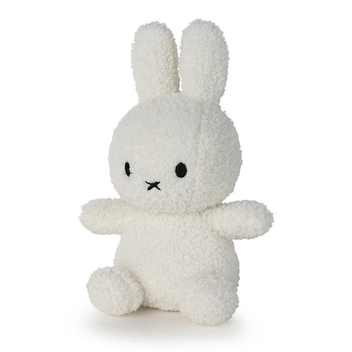 A white stuffed bunny toy with black eyes and a black nose is sitting on a white surface.
