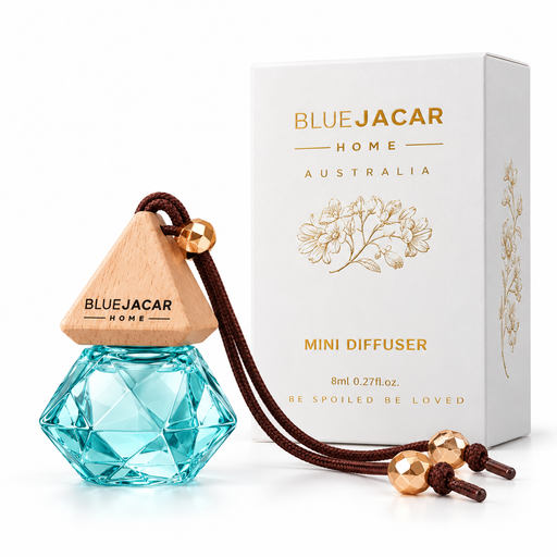 a Blue Jacar Home Mini Diffuser, a blue glass bottle with a wooden top, and a white box with gold text and graphics.