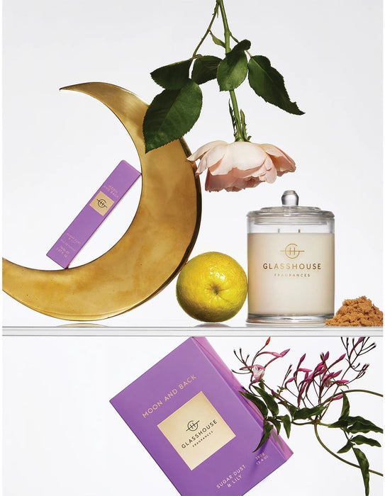 a collection of various objects, including a crescent moon, a candle, a lemon, and some flowers, arranged on a shelf.