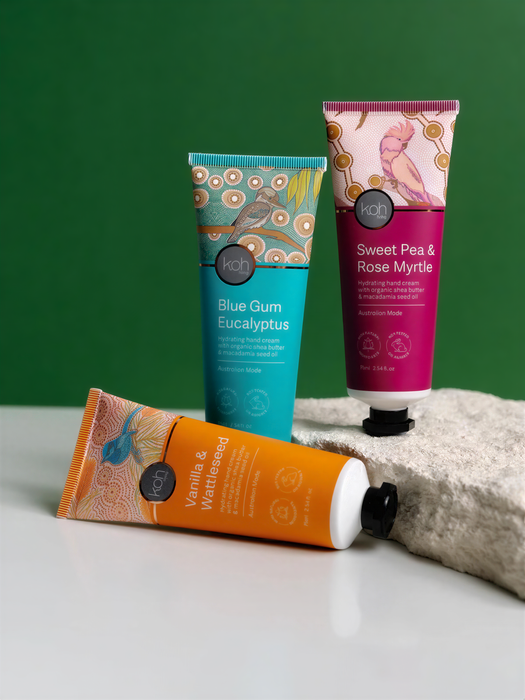 Three tubes of hand cream with different scents are displayed on a white surface against a green background.