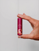 A hand holding a small, red lip balm with a label that reads "Native Berry Bliss".