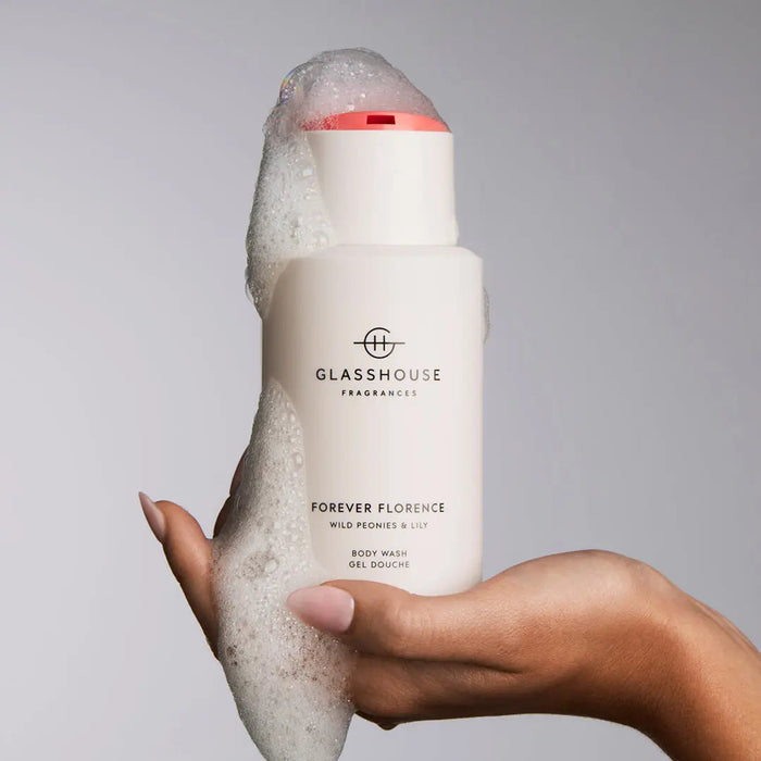 A hand holding a bottle of Forever Florence Wild Peony & Lilies Body Wash gel.