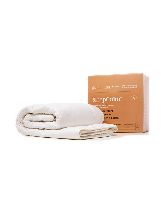 a folded white blanket and a cardboard box labeled "Sleeping Calm" next to each other.