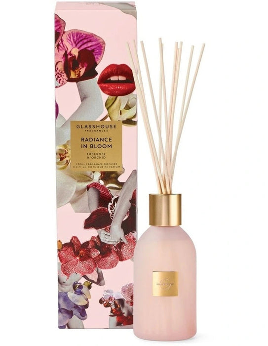 a pink glass diffuser with a gold-colored cap, and a pink box with a floral design and text.