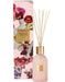 a pink glass diffuser with a gold-colored cap, and a pink box with a floral design and text.
