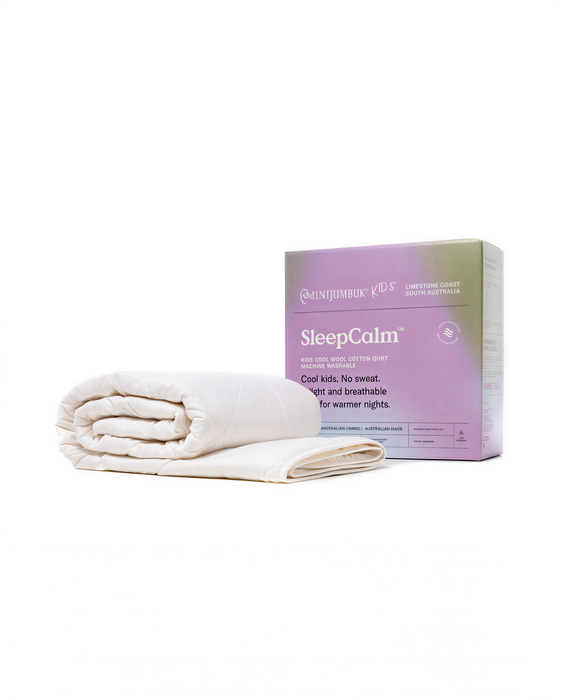 a white quilt folded and placed next to a purple box labeled "SleepCalm" on a white background.