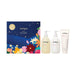 a set of three beauty products from the brand Jurlique, including a hand cream, a body lotion, and a shower gel, all displayed against a night sky background with flowers.