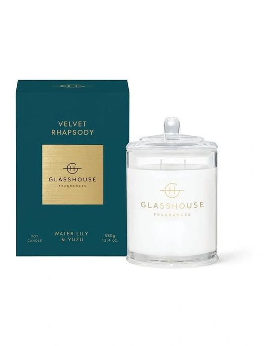 a green box and a clear glass jar of a candle from the brand GLASHOUSE. The box is labeled "VELvet RHAPSODY" and the jar is labeled "GLASHOUSE FRAGRANCES" and "WATER LILY & YUJU".