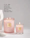 two pink candles, one larger and one smaller, with a white candle holder and a white object in the background.