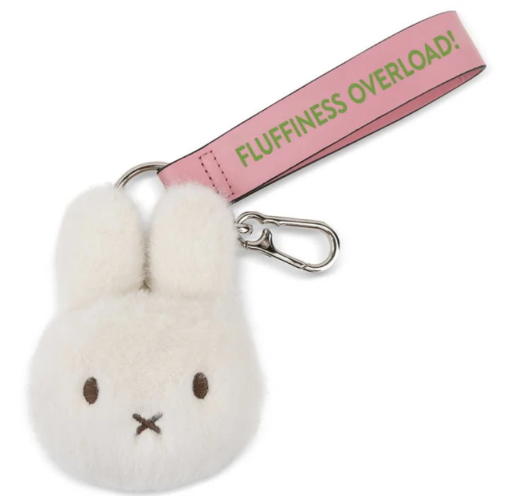 A white plush rabbit charm with a pink strap and a tag that says "FLUFFINESS OVERLOAD!"