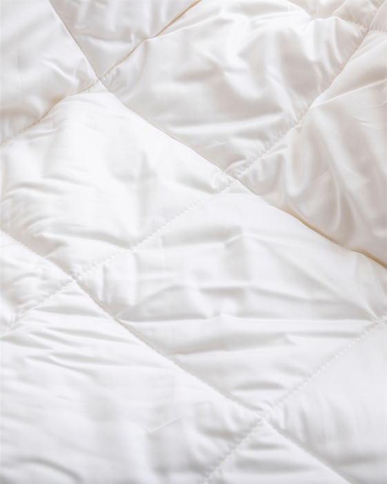 a close-up view of a white, crumpled fabric, possibly a blanket or quilt.