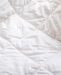 a close-up view of a white, crumpled fabric, possibly a blanket or quilt.
