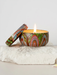 A colorful ceramic candle holder with a lit candle sits on a white rock, creating a warm and inviting atmosphere.