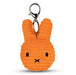 An orange, textured keychain in the shape of a rabbit's head with black eyes and a black nose.