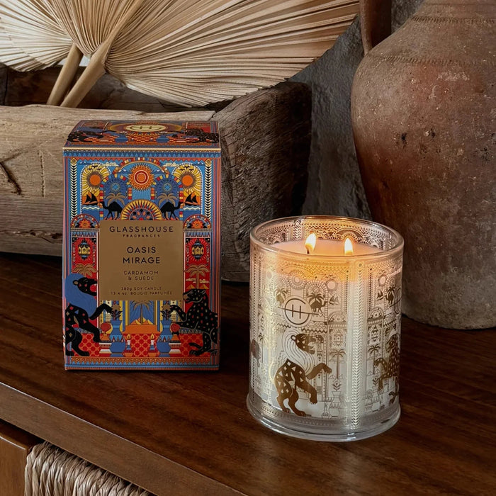 a glass candle holder with a lit candle inside, placed on a wooden surface next to a box of glass candles.