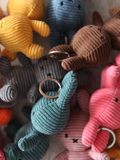 a collection of colorful stuffed animal keychains, including a yellow bunny, a blue elephant, a brown dog, and a pink bunny, arranged in a playful and visually appealing manner.