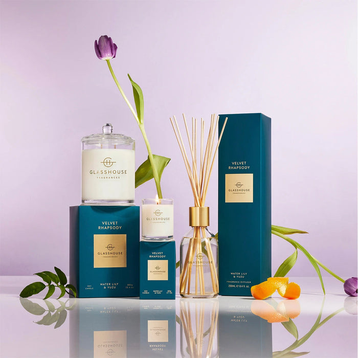 a collection of luxury products from the brand GLASHOUSE, including a candle, diffuser, and other accessories, all displayed on a reflective surface.