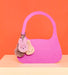 A pink handbag with three small, plush bunny keychains attached to it.