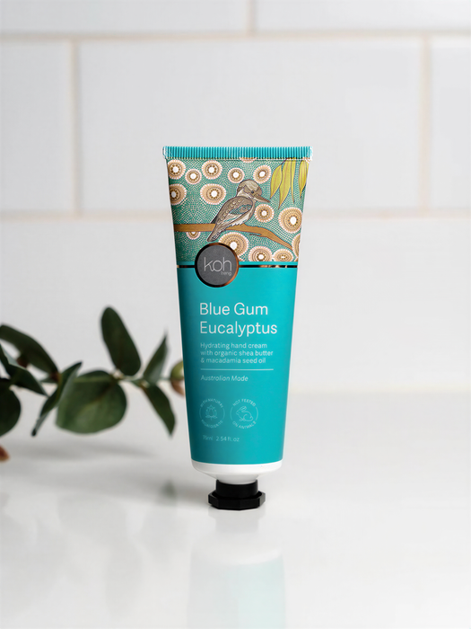 A tube of Blue Gum Eucalyptus Hand Cream with organic shea butter, placed on a white surface against a white tiled background.