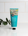 A tube of Blue Gum Eucalyptus Hand Cream with organic shea butter, placed on a white surface against a white tiled background.
