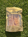 A package of dried meat, specifically "LING MAW", is lying on the grass.