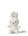 A white stuffed rabbit toy with black eyes and a black mouth is sitting on a white surface.
