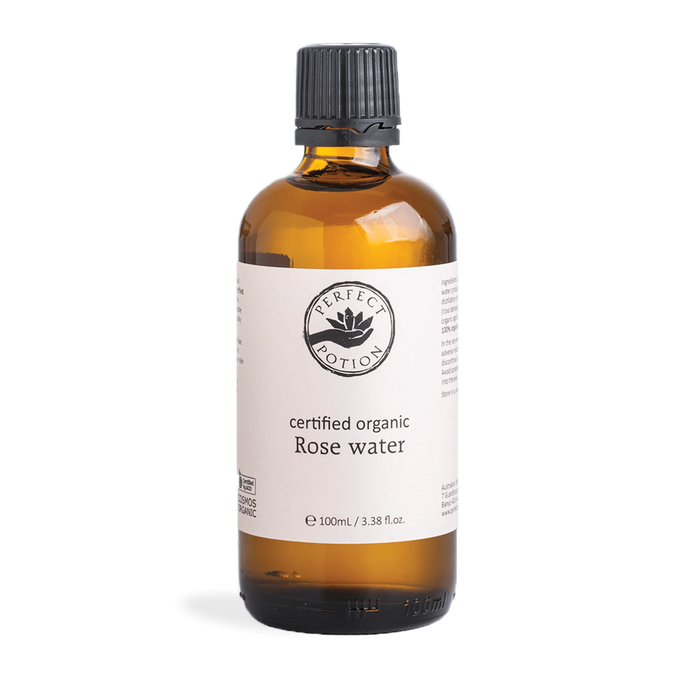 A bottle of certified organic rose water against a green background.