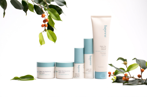 a collection of five skincare products from the brand Bayeco, arranged on a white background. The products include a tube of "Green Tea Cleansing Foaming Night Cream", a jar of "Green Tea Brightening Skin Cream", a jar of "Green Tea Nourishing Eye Cream", a tube of "Green Tea Serum", and a tube of "Green Tea Anti-aging Serum". The products are surrounded by leaves and branches, creating a natural and serene atmosphere.