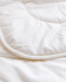 A close-up view of a white, fluffy, and soft-looking fabric, possibly a blanket or quilt.