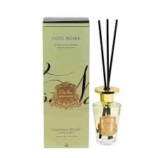 a glass diffuser with black reeds and a green box with gold lettering, both of which appear to be a product from the brand Cote Noire.