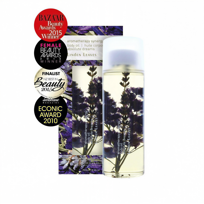 a bottle of liquid with purple flowers inside, placed on a white background. The bottle appears to be a beauty product, possibly a body oil or lotion.