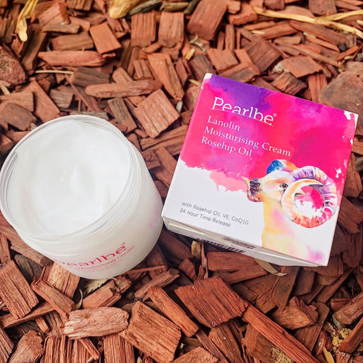 A jar of pearlbe skin care product and its packaging are placed on a bed of wood chips.