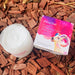 A jar of pearlbe skin care product and its packaging are placed on a bed of wood chips.