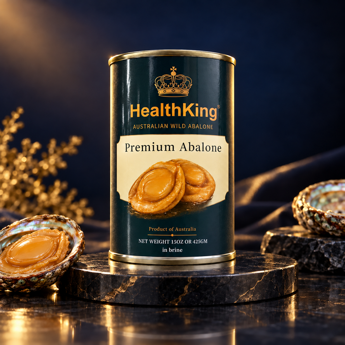 a can of HealthKing Premium Abalone meat, which is a product of Australia. The can is placed on a marble surface, with a small bowl of abalone shell in the foreground and a plant in the background.