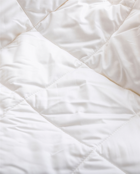 a close-up view of a white, crumpled fabric, possibly a blanket or quilt.