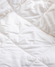 a close-up view of a white, crumpled fabric, possibly a blanket or quilt.
