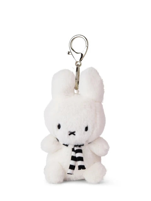 A small white plush bunny toy with a black and white striped scarf attached to it.