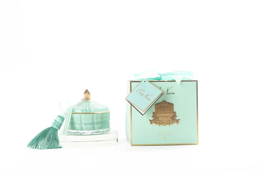 a mint green candle and a mint green box with a tassel, both placed on a white background.