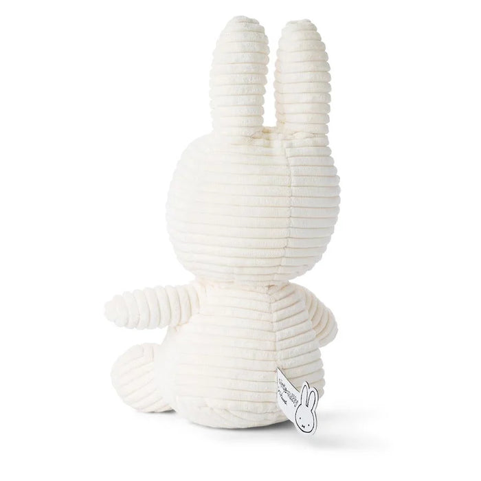 A white stuffed bunny toy is sitting on a white surface.