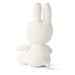 A white stuffed bunny toy is sitting on a white surface.