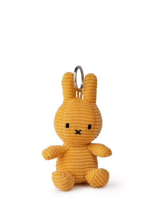 A yellow stuffed bunny toy with a black eye and mouth, hanging from a silver ring.